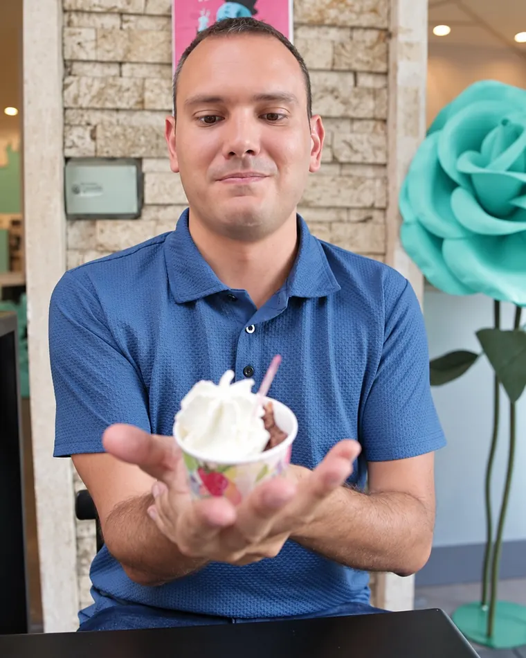 Un cliente con la coppetta davanti alla parete di fiori
